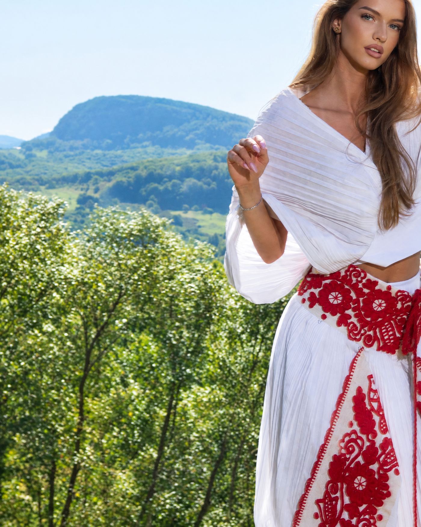 Woman in embroidered garment in Transylvanian landscape